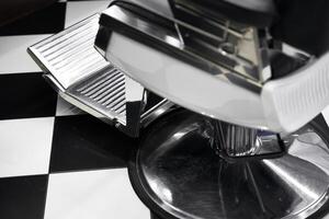 Vintage barber chair and footrest in classic black and white tiled barbershop photo