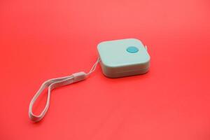 Close-up of a green soft measuring tape curled on a red background. Isolated and well-lit for use in design and advertising. photo