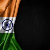 Ruffled Indian flag displayed on the left side against a dark wooden backdrop. photo