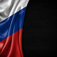 Silk fabric displaying the Russian flag draped elegantly against a textured black wooden background. photo