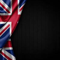 Presentation of the Union Jack flag, partially draped over a dark, textured wooden background. photo