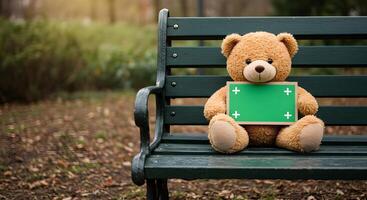A plush bear sitting on a bench holding up an empty green chroma key sign photo