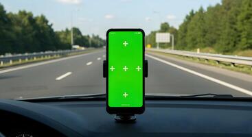 Smartphone displaying chroma key screen mounted on a vehicle dashboard offering a view photo