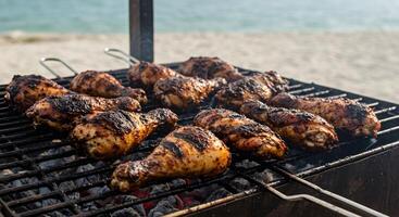Succulent barbecued chicken legs tantalize on an outdoor beach grill setting photo