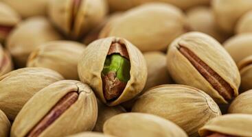 A close-up shot showcases a collection of pistachios, some with open shells and vibrant green nuts. photo