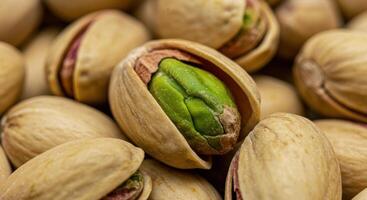 Close-up image showcases pistachios, one open to reveal the vibrant green nut. photo