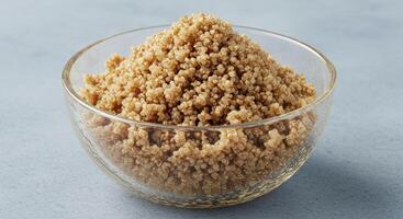 A clear glass bowl filled with fluffy, cooked quinoa against a subtle, soft background. photo