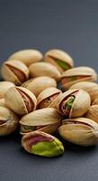 A close-up image presents fresh pistachios, some open, against a dark backdrop. photo