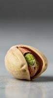 An isolated pistachio nut, partially open, showing its vibrant green kernel. photo