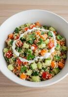 A beautiful bowl of quinoa salad with colorful vegetables and creamy dressing. photo
