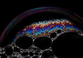 Vibrant colors dance across a soap bubble surface, creating a mesmerizing, detailed display. photo