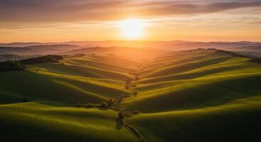 The setting sun casts a warm glow over the rolling green hills, creating a picturesque landscape. photo