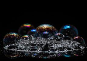 Intricate soap bubbles shimmer with iridescent colors against a contrasting black background. photo
