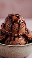 A close up shot of creamy chocolate ice cream in a textured bowl, with sauce and chocolate. photo