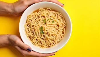 Holding a Bowl of Spaghetti Noodles Soup on Yellow Background photo