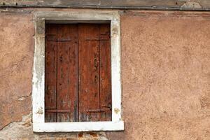 Old rustic window with weathered wooden shutters on textured wall photo