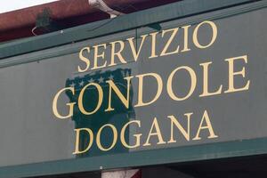 Venice, Italy - April 20 2025 Gondola service Dogana signboard at canal-side boarding area in Venice photo