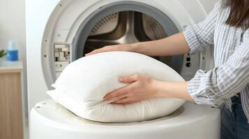 Woman Placing White Pillow Into Modern Washing Machine For Cleaning photo