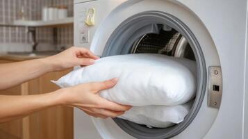 Loading Freshly Washed Pillows into the Washing Machine at Home Laundry photo