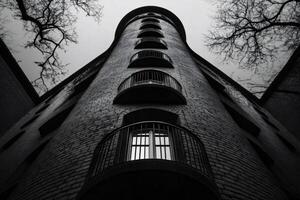 Low angle view of brick building with balconies reaching for cloudy sky photo
