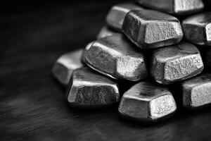 Stack of metal ingots forming a pyramid on dark wooden surface photo