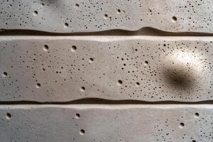 Textured concrete wall showing relief and holes creating unique pattern photo