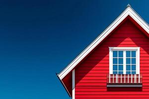 Red wooden house with white trim and window against blue sky photo