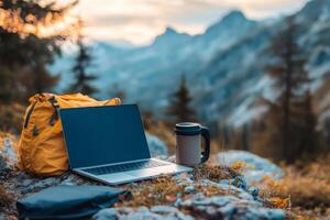 Laptop and backpack enabling remote work in mountain scenery at sunset photo