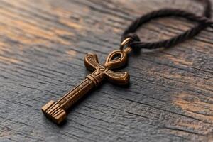 Ankh pendant resting on rustic wooden surface representing eternal life photo