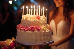 Bride smiling looking at beautiful wedding cake with lit candles and roses photo