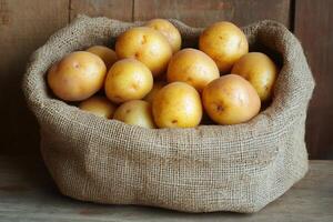 Raw potatoes resting in a burlap sack on a wooden table photo