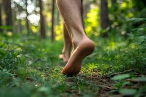 Man walking barefoot on green grass in forest enjoying nature photo