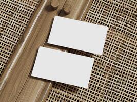 Two blank business cards positioned on a rattan background with a polished wooden border, ideal for professional branding. photo