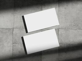 Business card mockup placed on a concrete floor, highlighting the simplicity and elegance of corporate design. photo