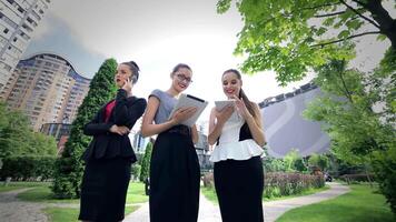 Three successful businesswomen collaborating on tablets while taking calls video
