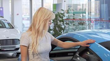 Charming woman smiling brightly while leaning on a sleek new car at a dealership video