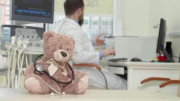 Dedicated male pediatrician analyzing MRI scan with a plush teddy bear in focus video