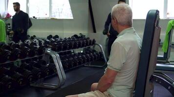 allenatore mani manubri per anziano cliente nel un' Palestra video