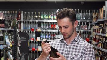 Charming young man joyfully selecting a wine bottle in a vibrant supermarket video
