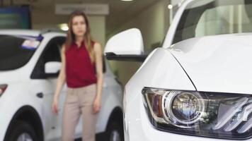 Female customer thoughtfully examining a sleek new car at the dealership video