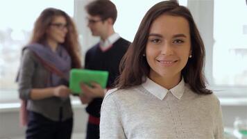 Engaged team members collaborate over a tablet while a smiling woman stands confidently in the foreground video