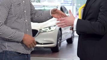 Car dealer shaking hands with client while handing over car keys video