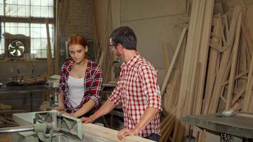 Dynamic duo of young carpenters collaborating on woodwork in a bustling workshop video