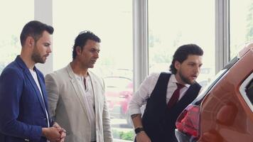 Three men excitedly exploring the trunk of a new car at the dealership video