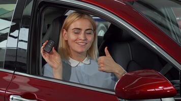 Joyful female driver proudly displaying her car keys with a thumbs up video