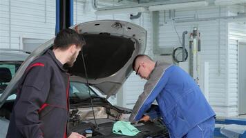 Young mechanic troubleshooting car issues with a focused partner at the service station video