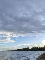 A beach with a body of water and a sky photo