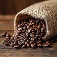 Roasted coffee beans spilling from a burlap sack on a rustic wooden table. photo