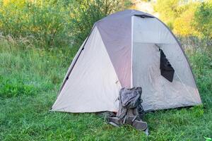 A tent in the grass with a backpack on it photo