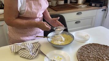 Flour is sifted in to batter in the bowl video